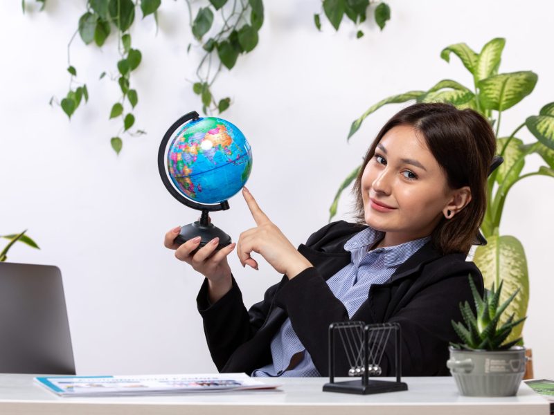 front-view-beautiful-young-businesswoman-black-jacket-blue-shirt-observing-little-globe-smiling-front-table-business-job-office (2) (1)